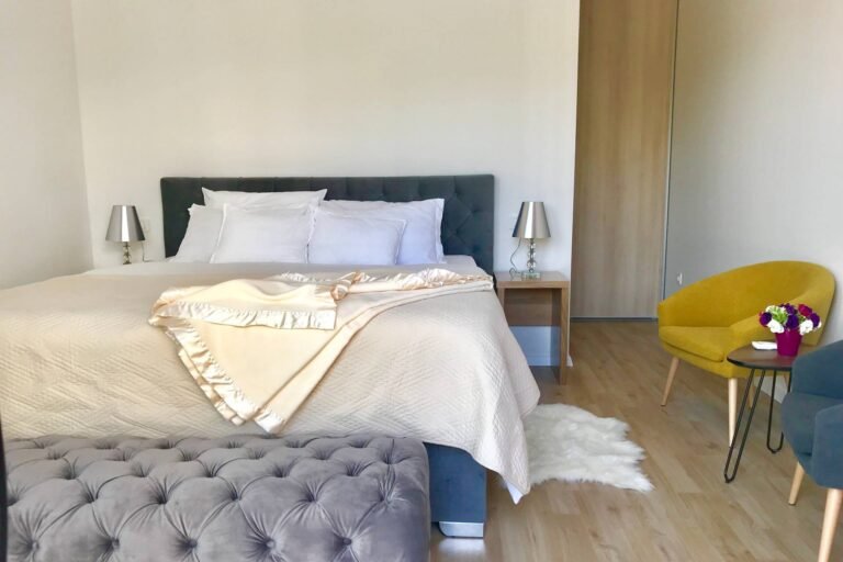 Bedroom with king-size bed, velvet headboard and yellow armchair at Villa Aether