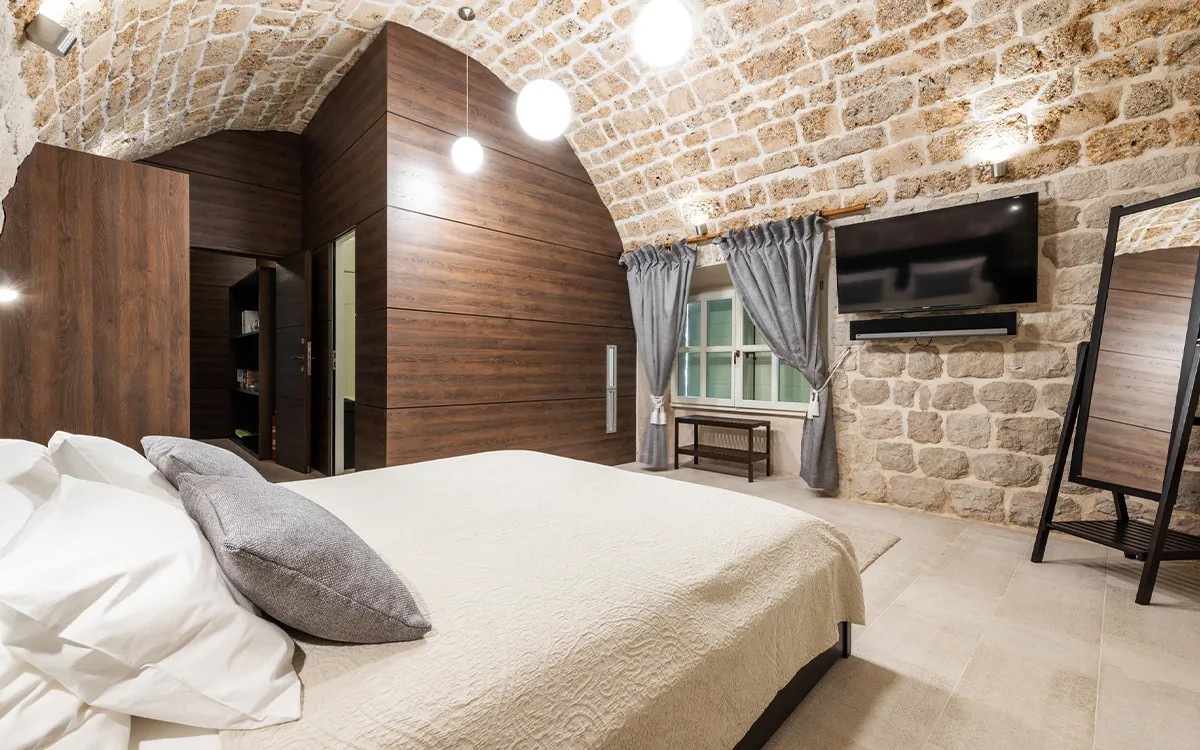 Schlafzimmer mit Kingsize-Bett unter einem gewölbten Steildach in der Villa Carpe Diem