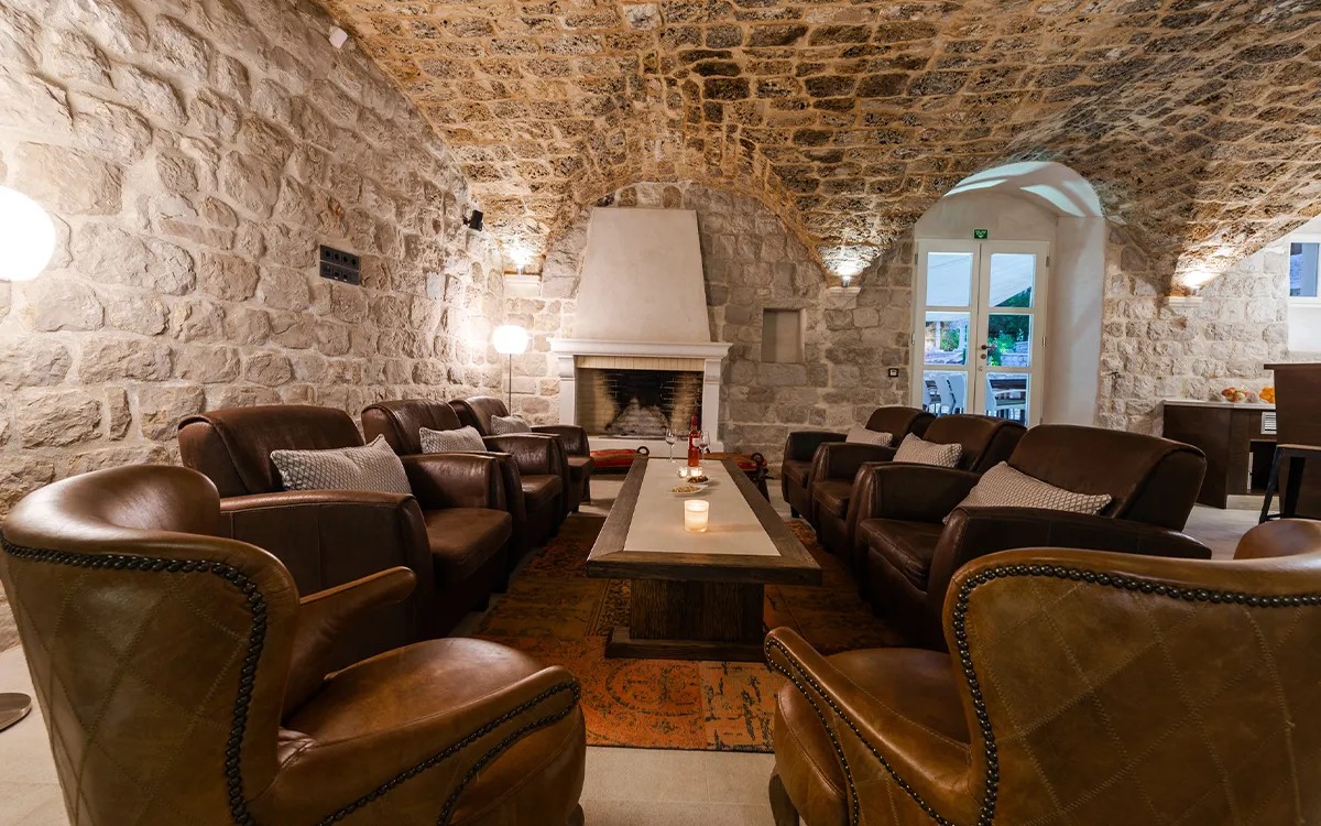 Steinhöhlen-Saal mit Ledersesseln und Kamin in der Villa Carpe Diem
