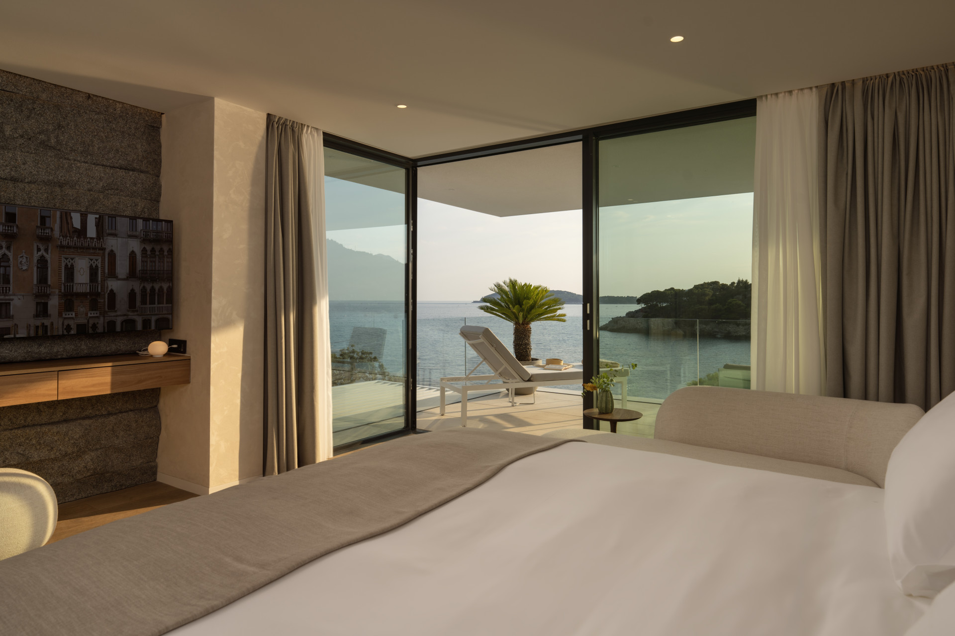 Schlafzimmer mit Kingsize-Bett und Eckfenster zu einer Sonnenterrasse in der Villa Klara