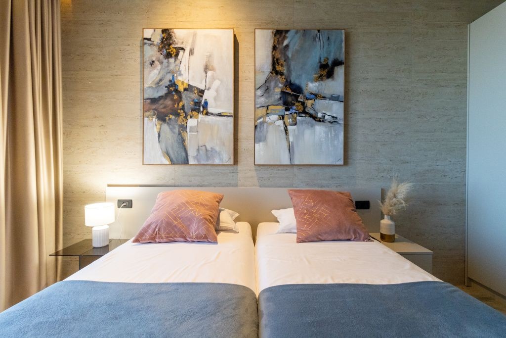 Zweibettzimmer mit zwei Einzelbetten und abstrakten Kunstwerken in der Villa La Frida