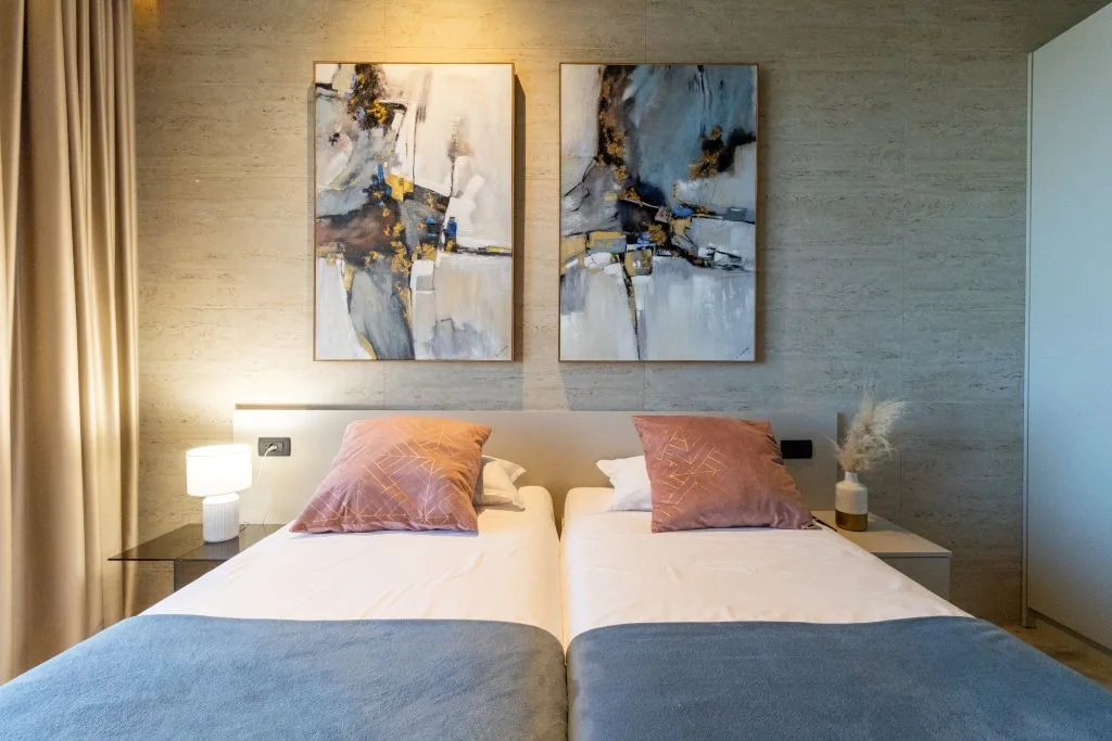 Twin bedroom with two single beds and abstract artwork at Villa La Frida