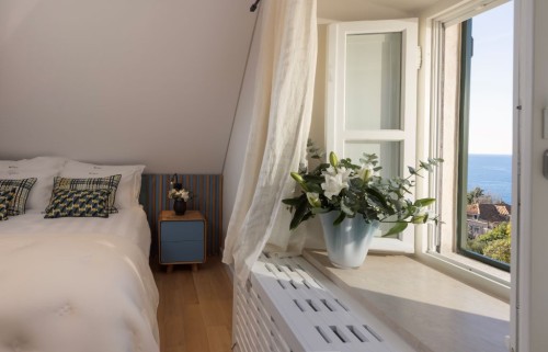 Schlafzimmer mit Kingsize-Bett und offener Fensterfront mit Blick auf das Meer im Nebengebäude der Villa La Rose in Dubrovnik