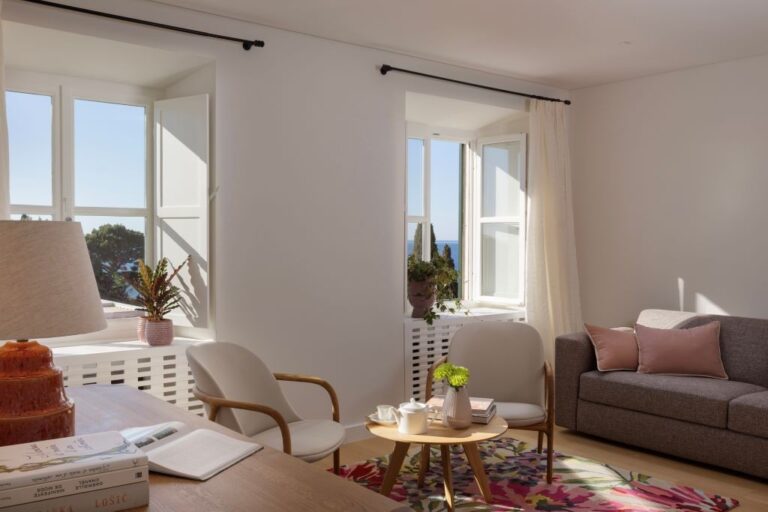 Wohnzimmer mit ausziehbarer Sofa, Sesseln und Fenstern mit Meerblick in der Villa La Rose