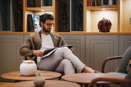 Guest reading in the library lounge with bookshelves at Villa La Rose