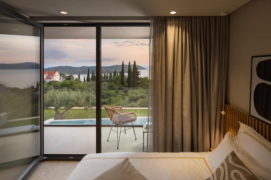 Schlafzimmer mit Kingsize-Bett, das auf eine Terrasse mit Pool, Olivenbäumen und Meerblick führt, in der Villa Ó