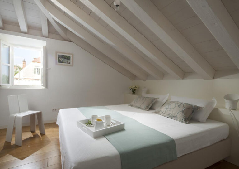 Attic-Schlafzimmer mit Kingsize-Bett unter weißen Holzdächern in der Villa Oasis in Dubrovnik