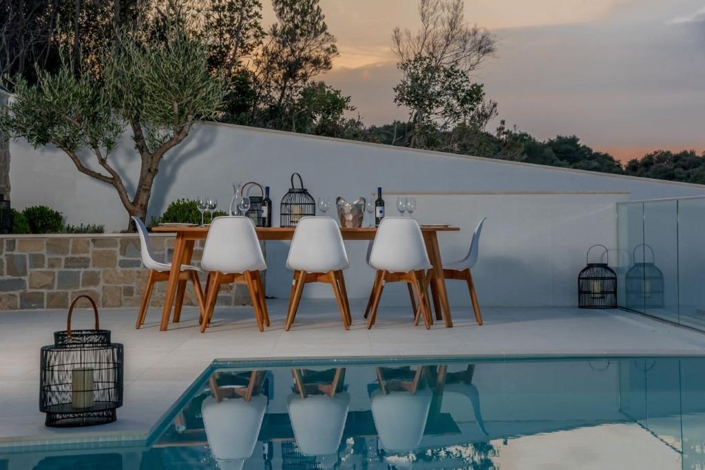 Outdoor dining table by the pool at sunset at Villa Opus, Korčula